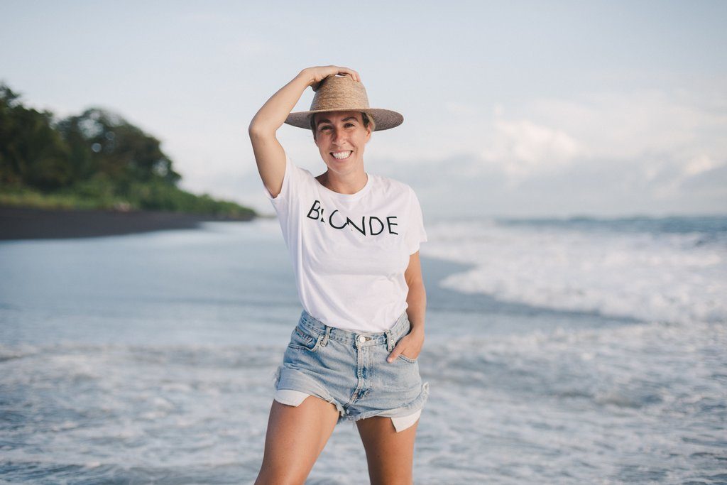 Yoga instructor Ally Maz photographed on the beach in a white tshirt from Brunette the Label. 