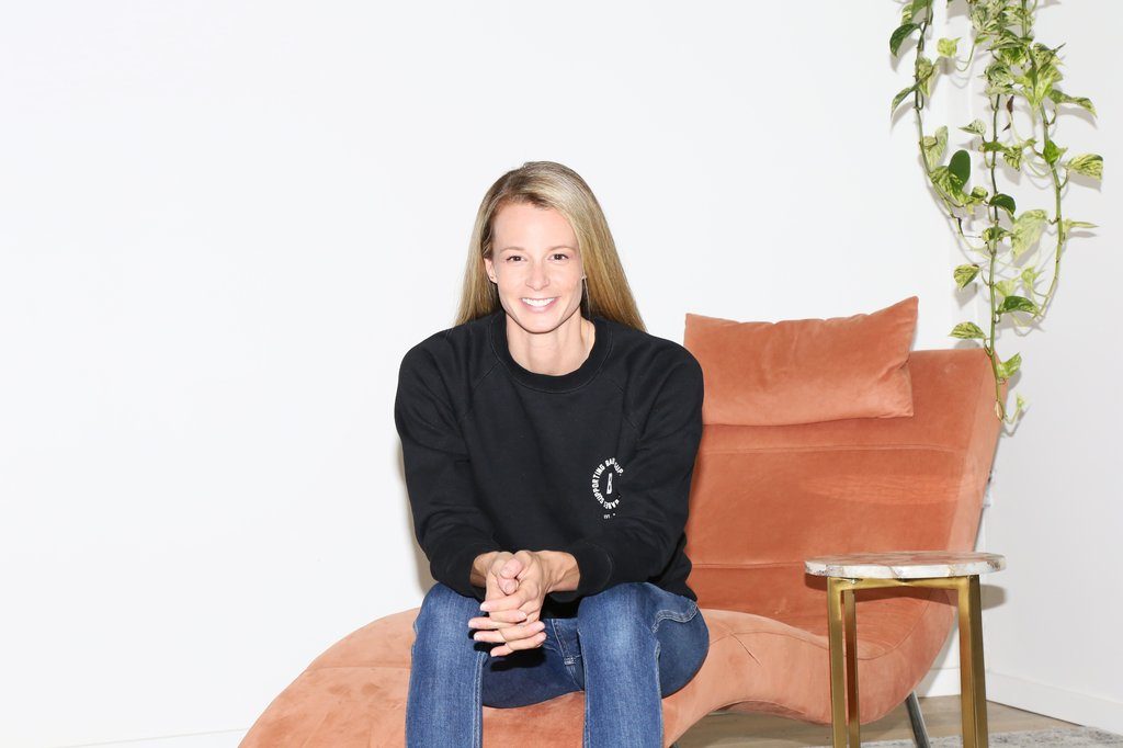 Erin Treload, founder of Raw Beauty Talks photographed sitting on a chair wearing a sweatshirt from Brunette the Label.